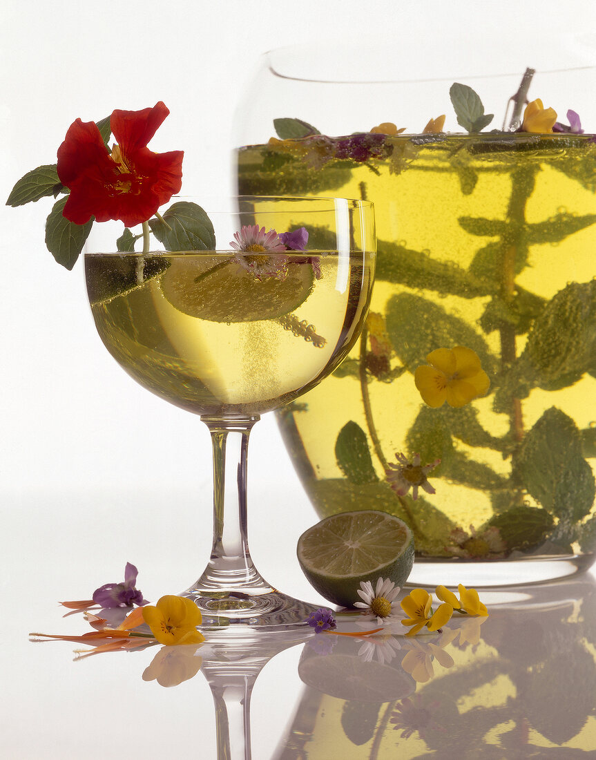 Herbal punch with garnishing of flowers in glass and jar