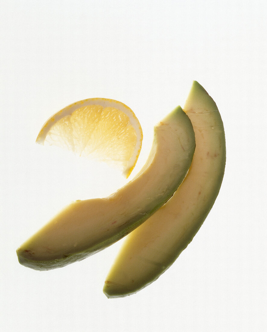 Slices of avocado and lemon on white background
