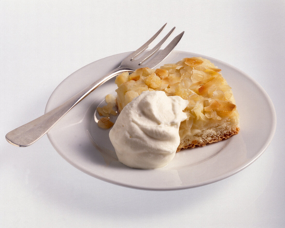 Yeast apple pie with whipped cream on plate