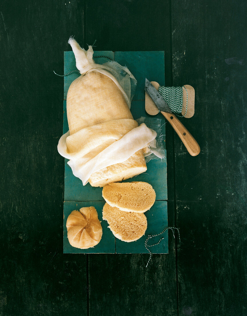 Sliced bread wrapped in white napkin with knife on table