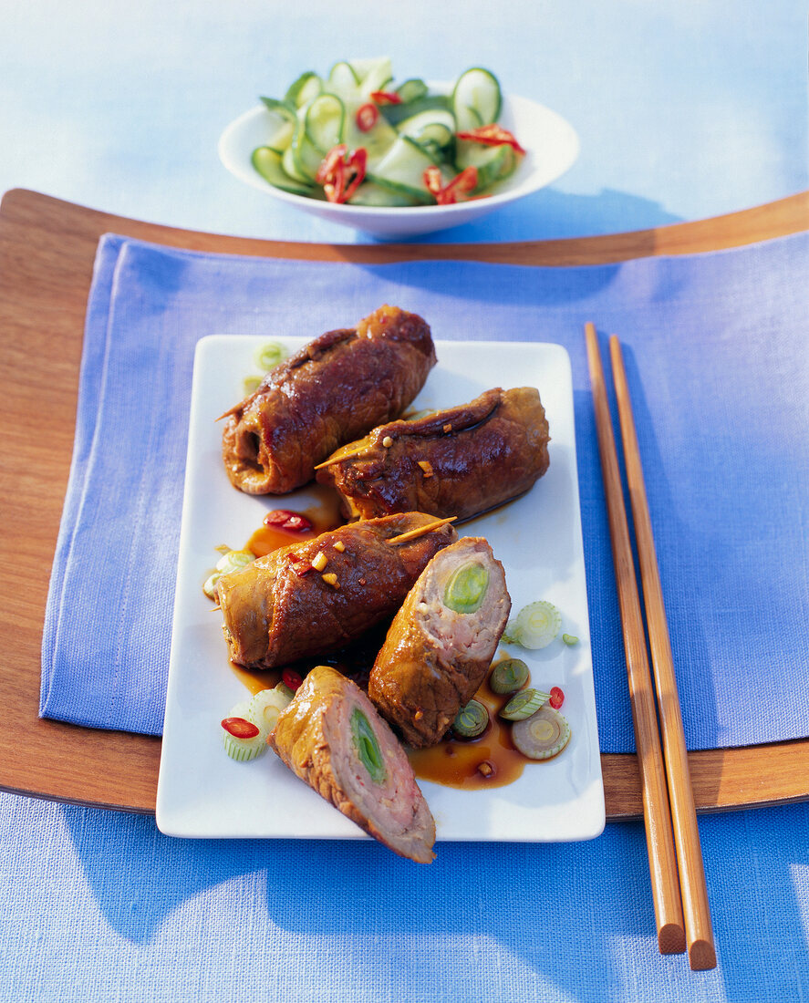 Pork rolls with cucumber on white plate