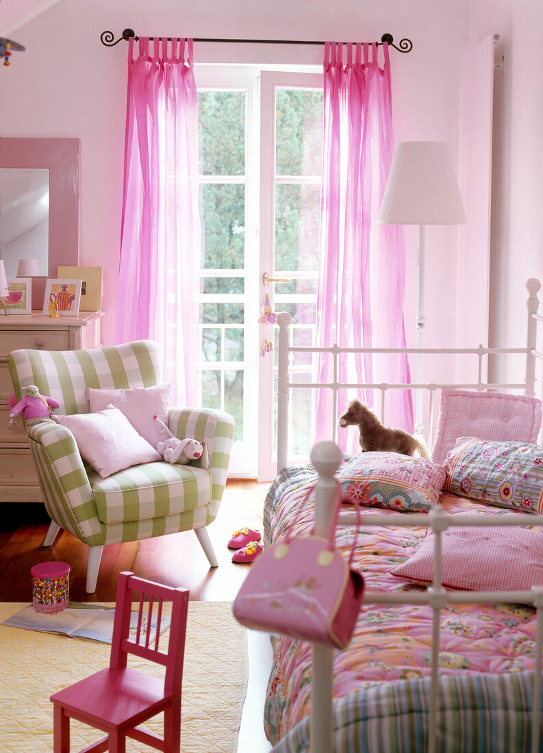 Children's room decorated with pink coloured bed, small chairs and arm chairs