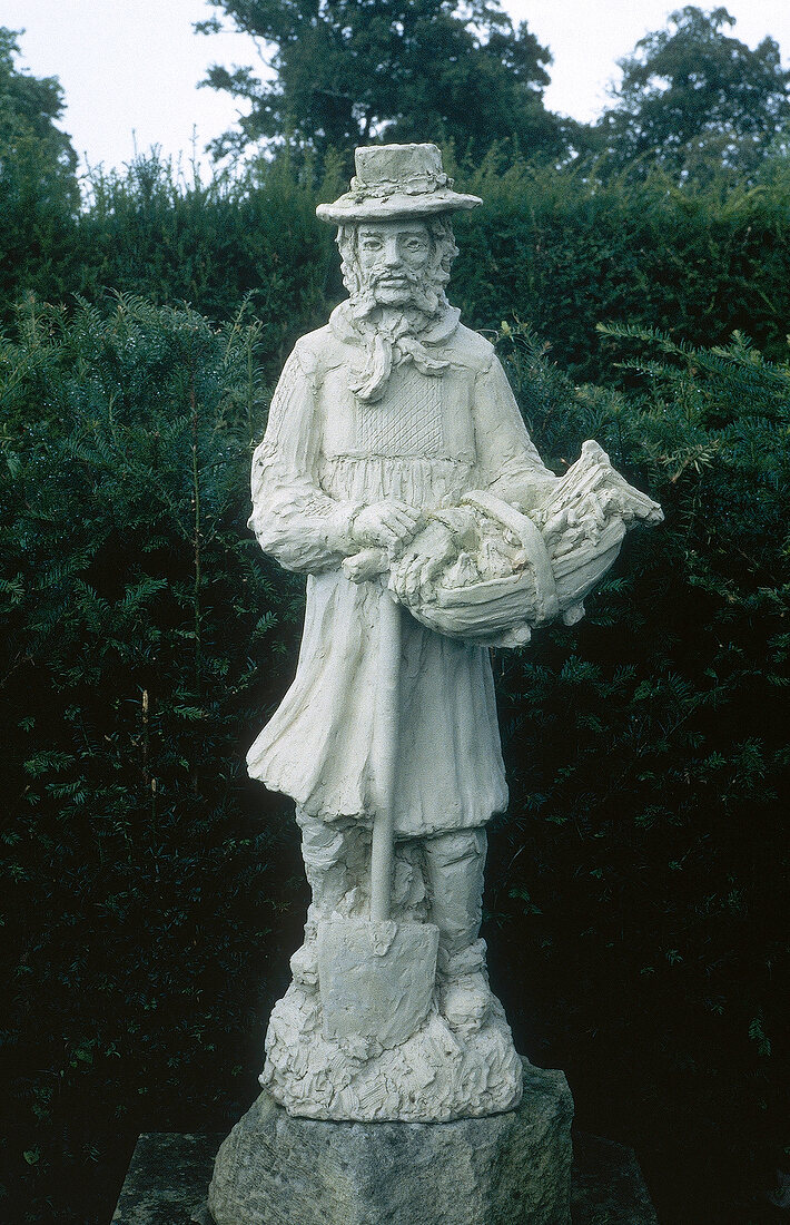 White statue of a medieval English gardener in the garden