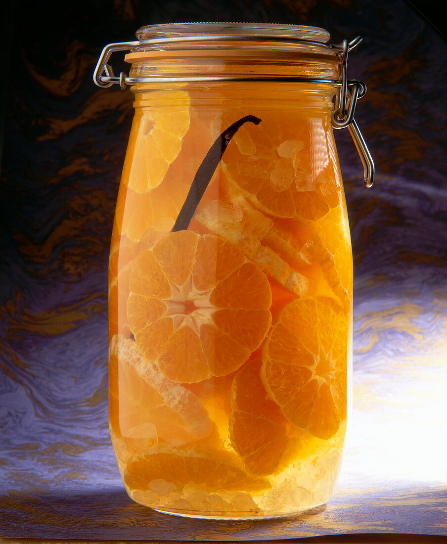 Mandarinen in Weizenkorn im Glas, mit Kandis und Wacholderbeeren
