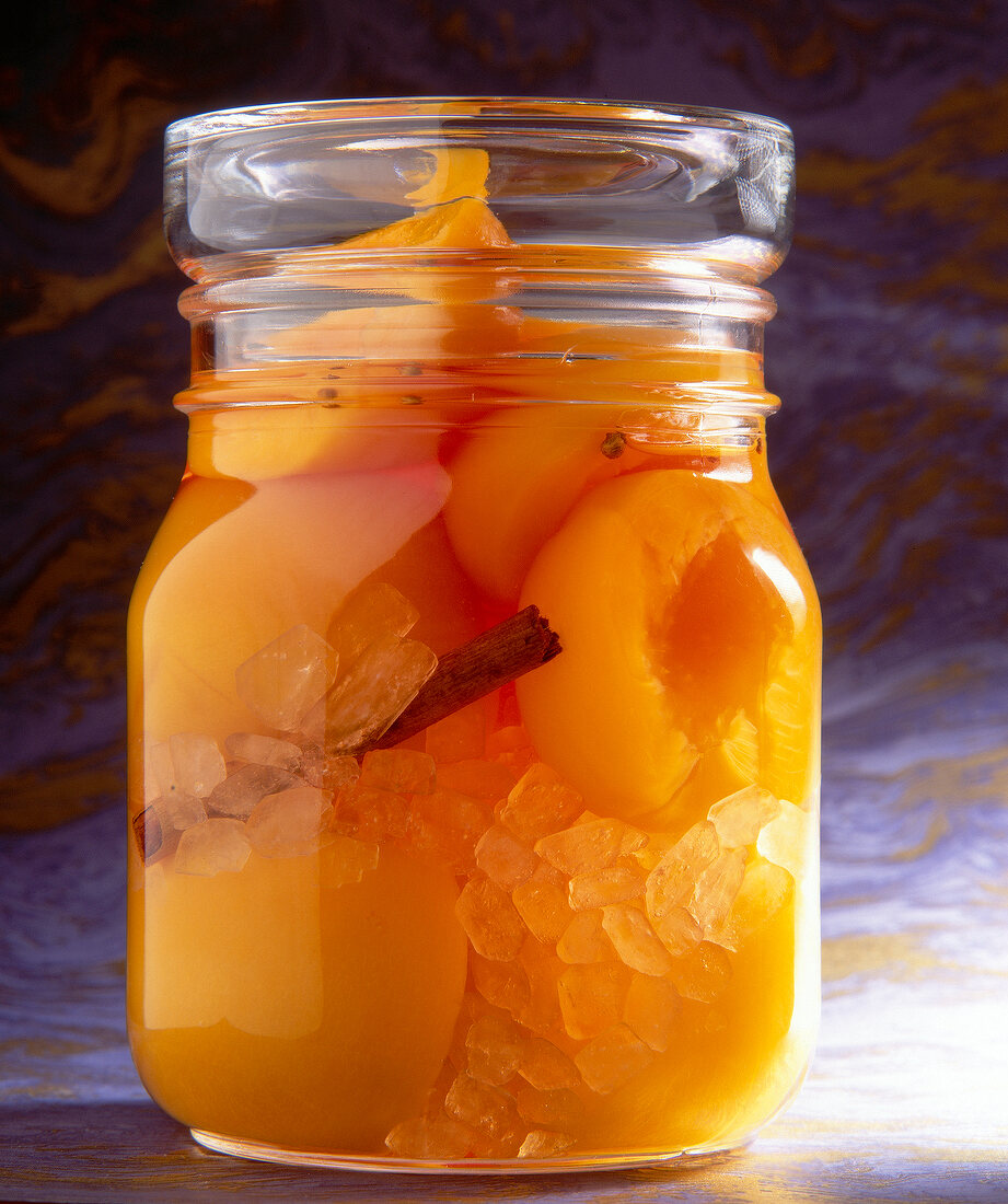 Peaches, cinnamon and coriander with vodka in glass jar