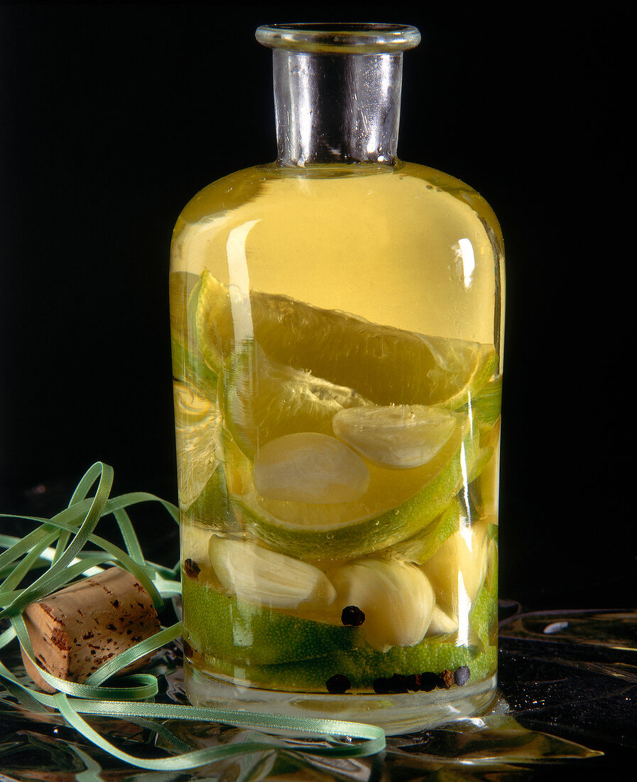 Bauchige Flasche Knoblauch-Öl mit Limette, Zitrone und Pfefferkörnern