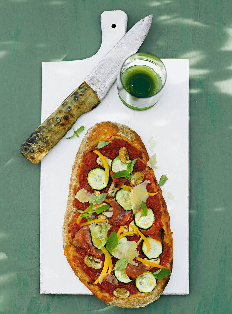 Pizza with zucchini, ham and mushrooms on white board