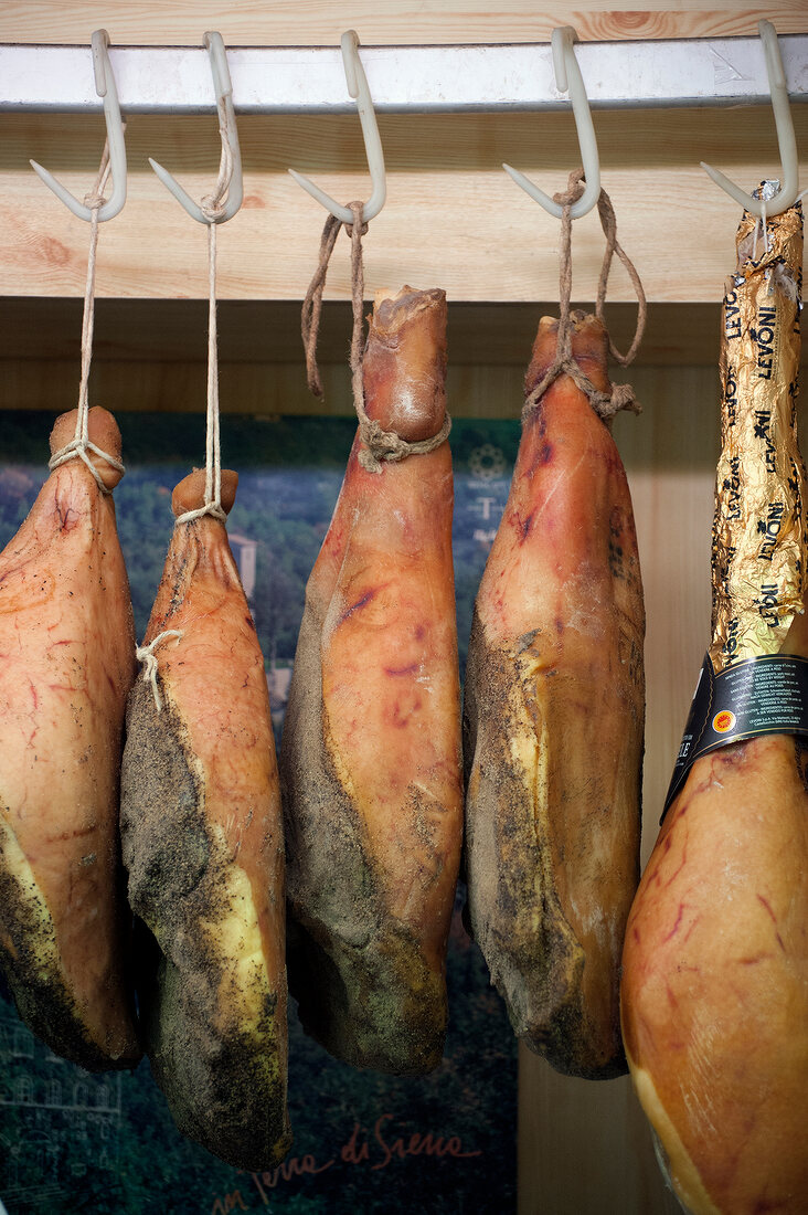 Whole Parma hams hanging on hooks