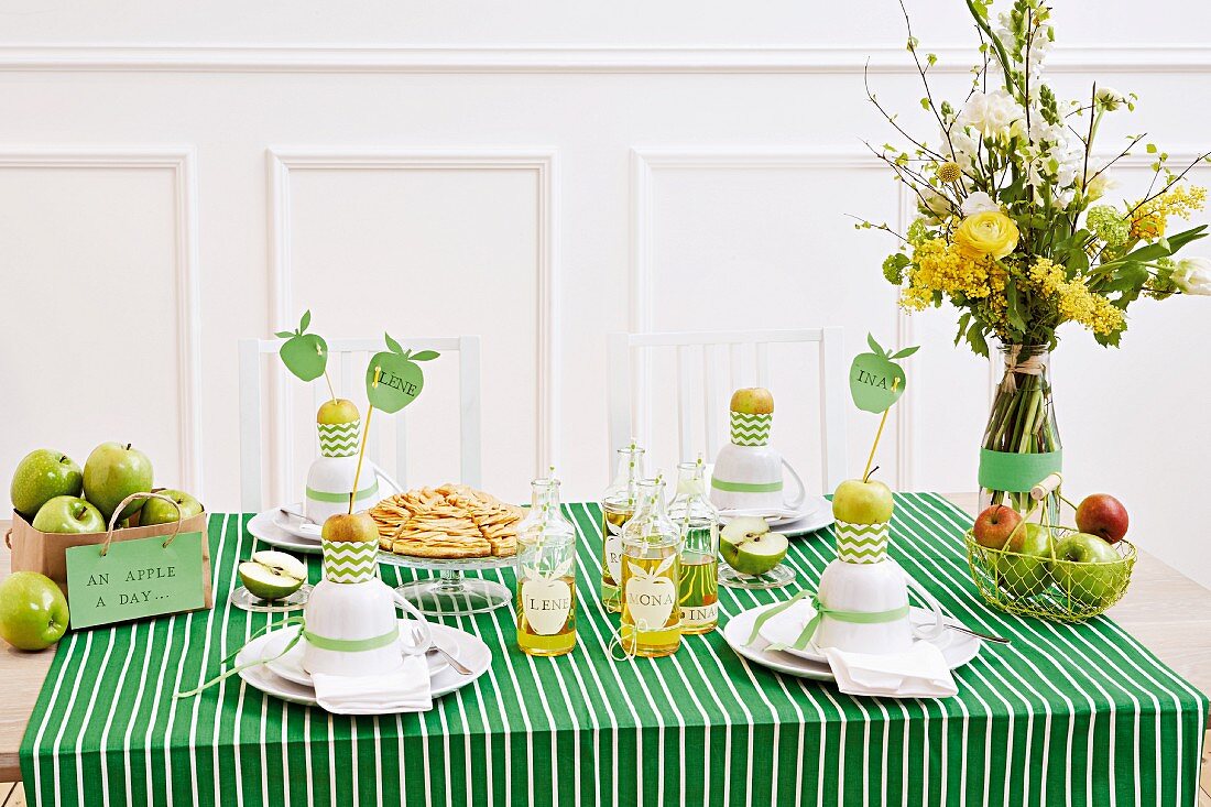 Gedeckter Tisch mit grün-weiss gestreiftem Tischtuch und frischen Äpfeln