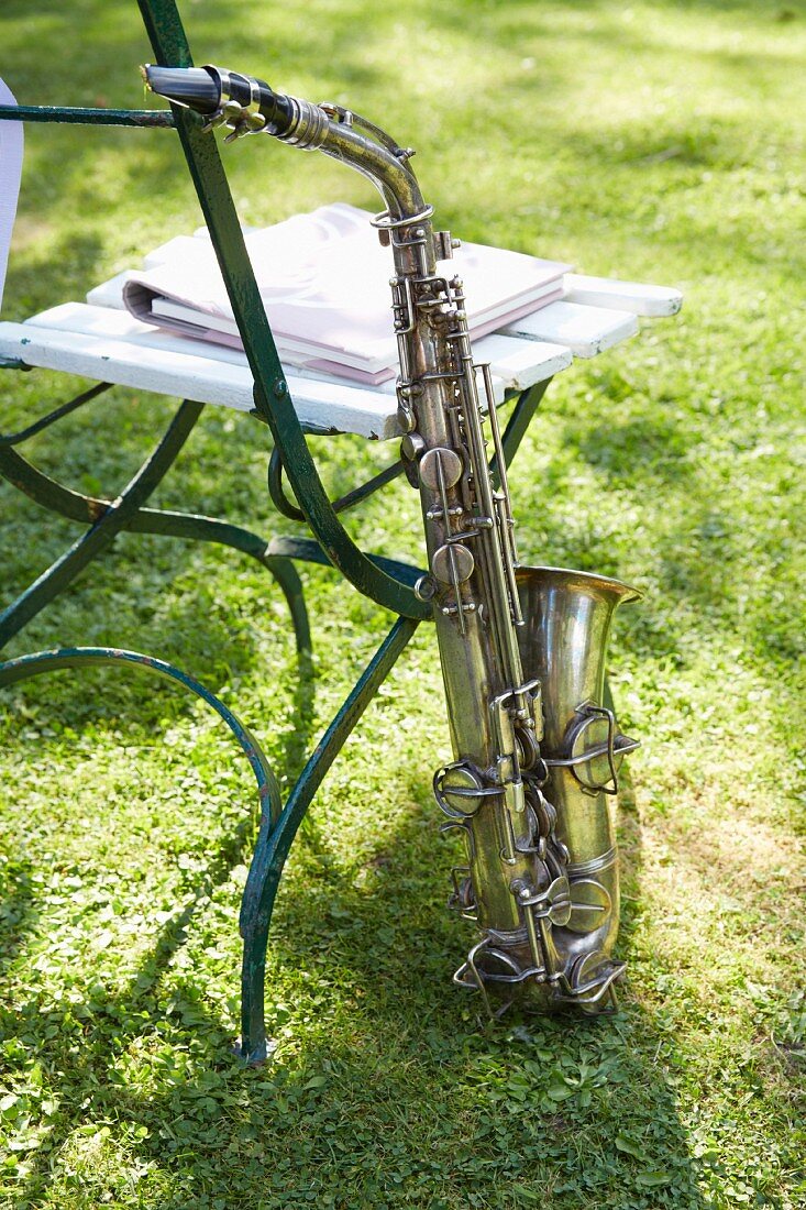 A saxophone on the grass leaning against a garden chair