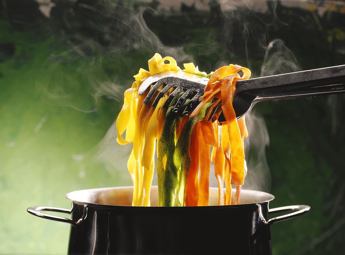 Pasta Tong Lifting Assorted Tagliatelle Out of a Steaming Pot