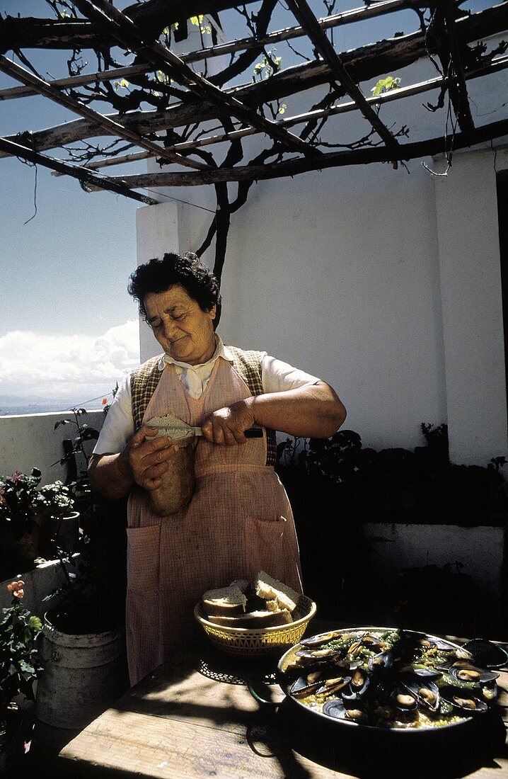 Frau schneidet Brot auf einem Balkon in Spanien
