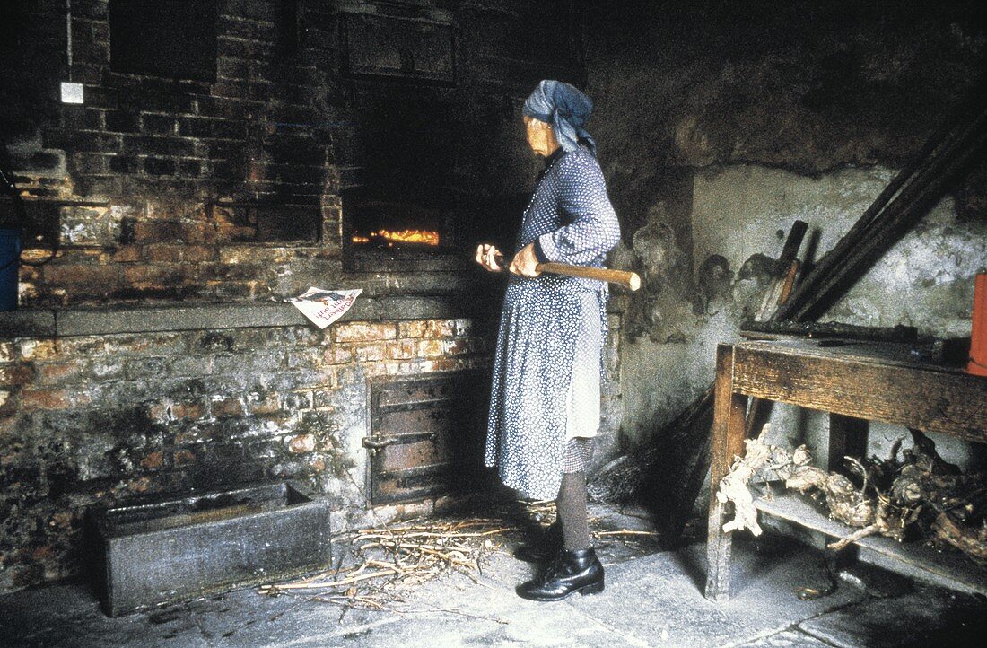 Alte Frau beim Brotbacken