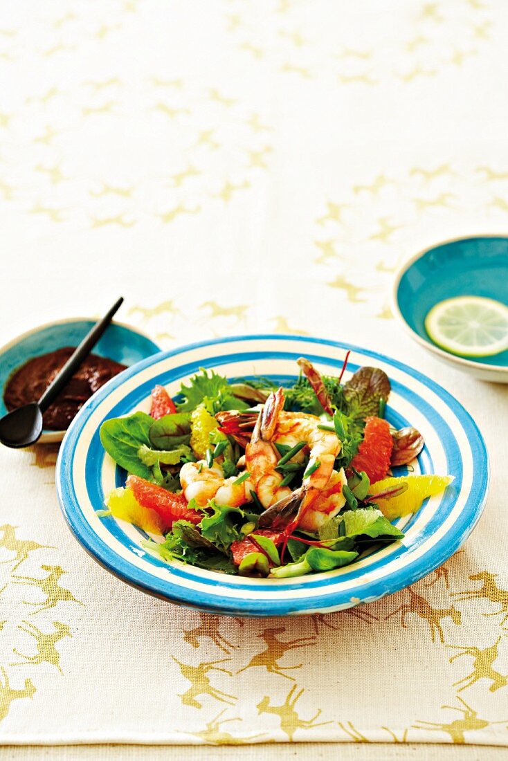 A salad of prawns with citrus fruits, and a bowl of harissa paste