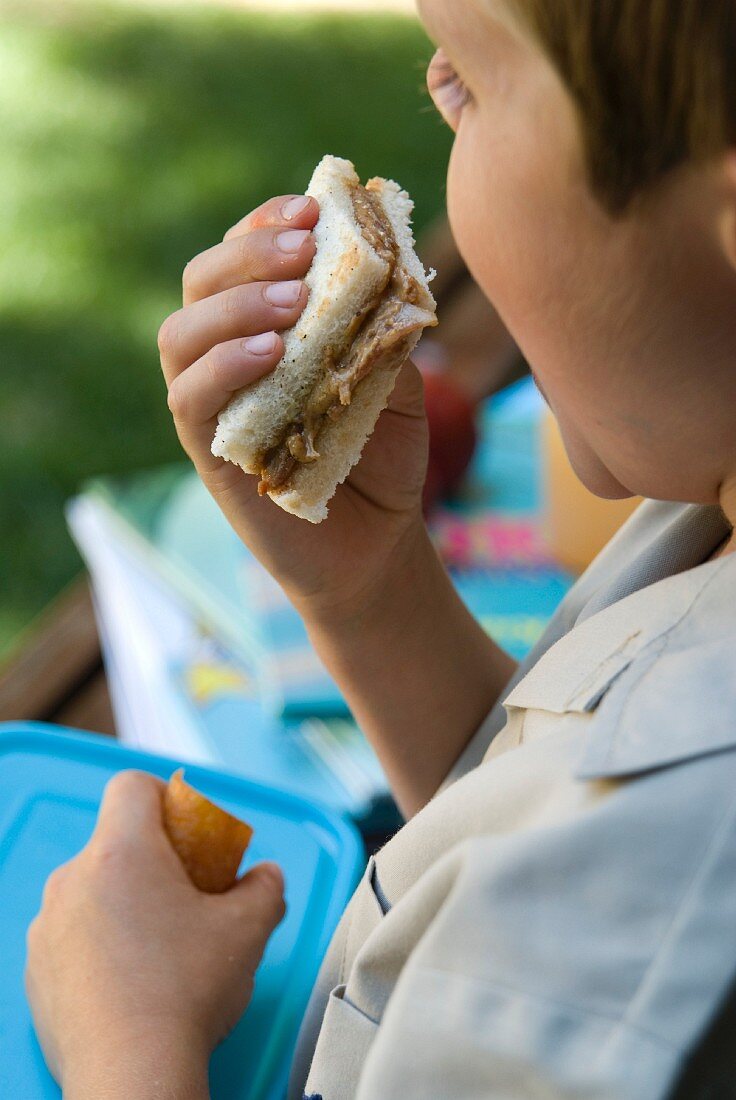 A boy eating a peanut butter and bacon sandwich