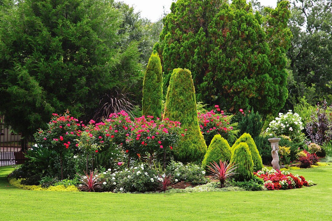 Elegant gardens with stone statue and luxuriantly flowering plants