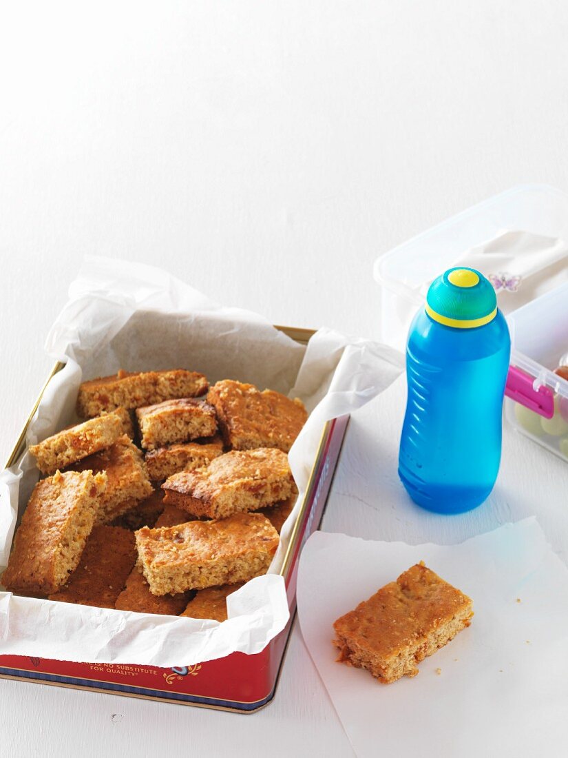 Muesli bars with apricots and honey, a bottle of water and a lunchbox