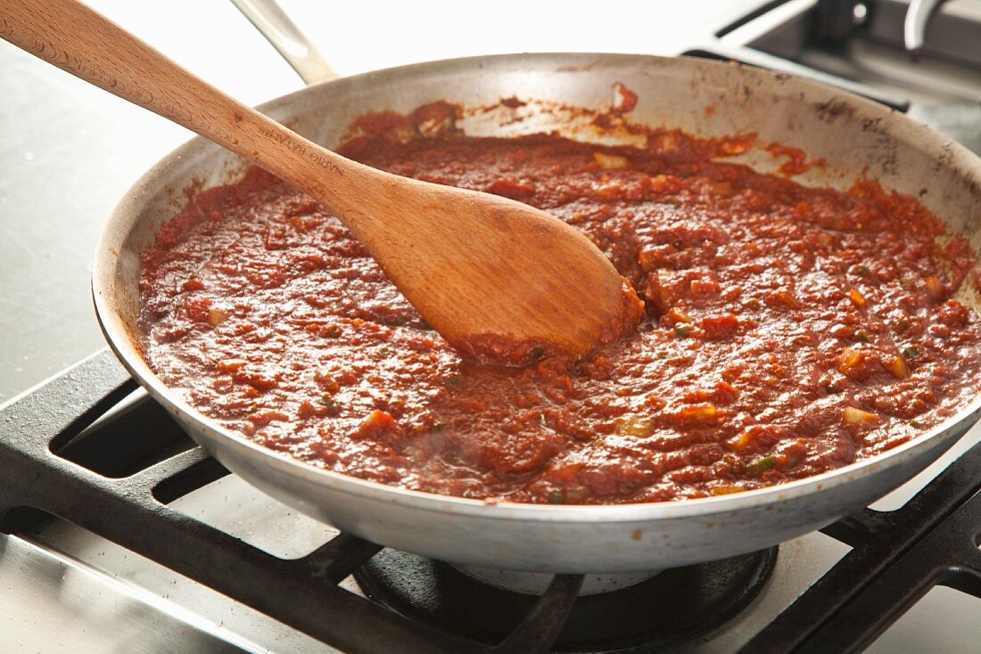 Chili zubereiten (Tomatenpüree in Gemüse einrühren)
