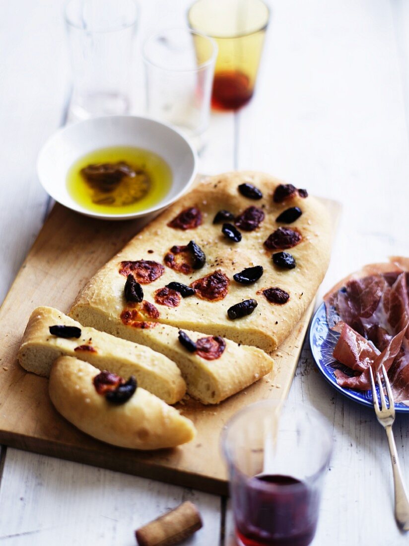 Schiacciata mit schwarzen Oliven, dazu Parmaschinken