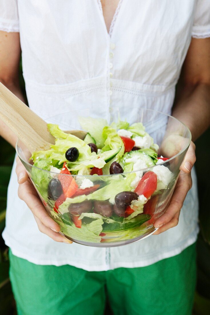 Frau serviert Schüssel mit Griechischem Salat