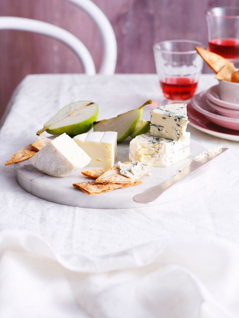 A cheese platter with crackers and pears