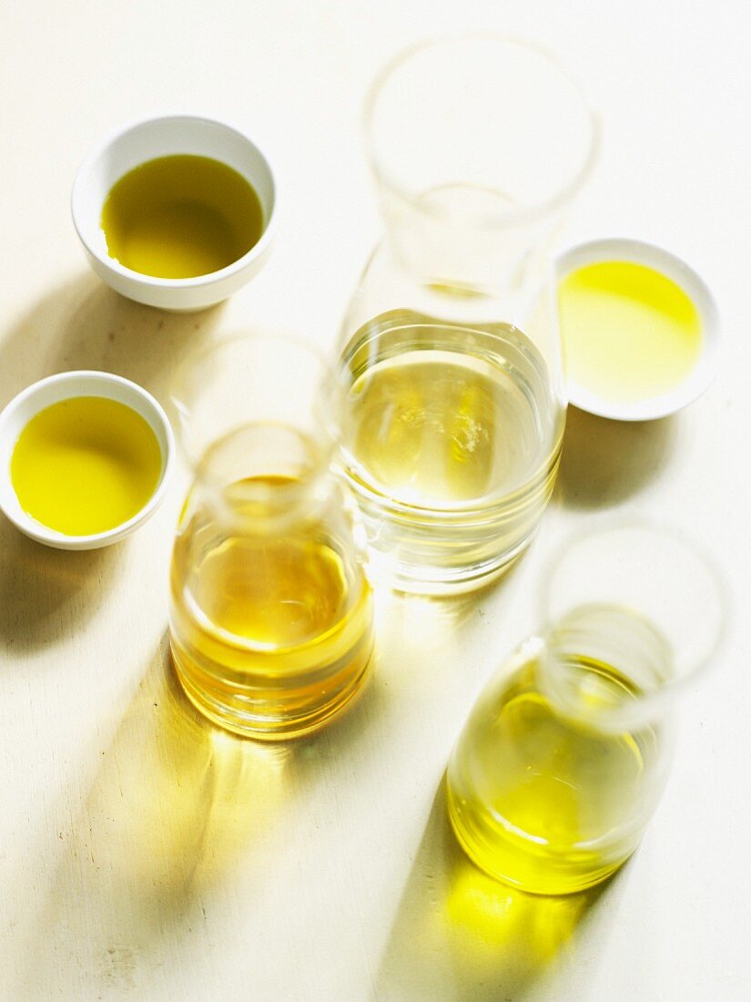 Verschiedene Olivenölsorten in Karaffen und Schalen