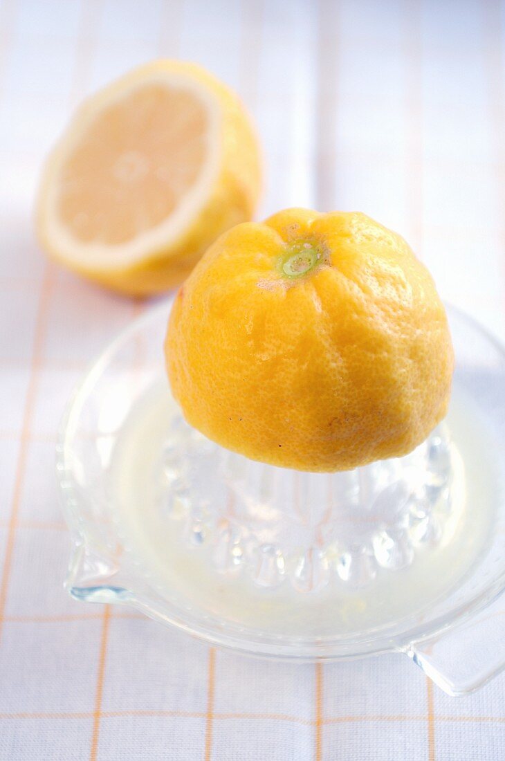 A lemon half on a glass citrus press