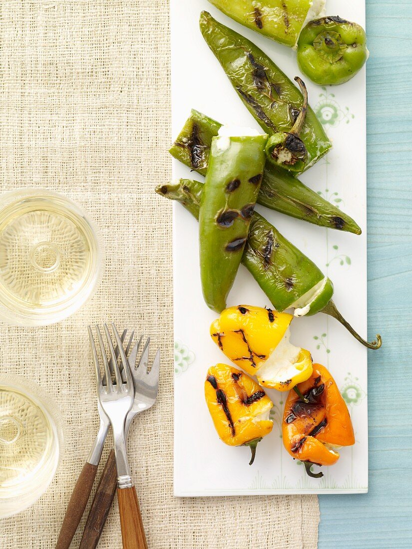 Grilled Stuffed Peppers on a Platter; Glasses of Wine; Forks