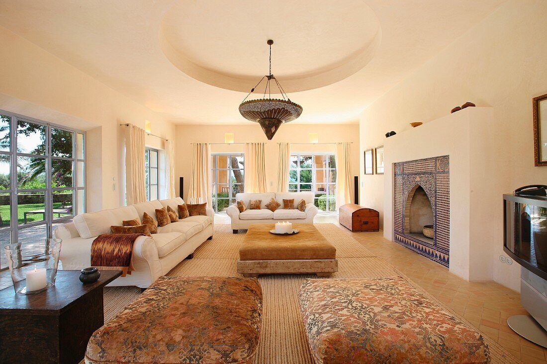 Helle Sofagarnitur und gepolsterte Couchtische in elegantem Wohnraum einer Landhausvilla