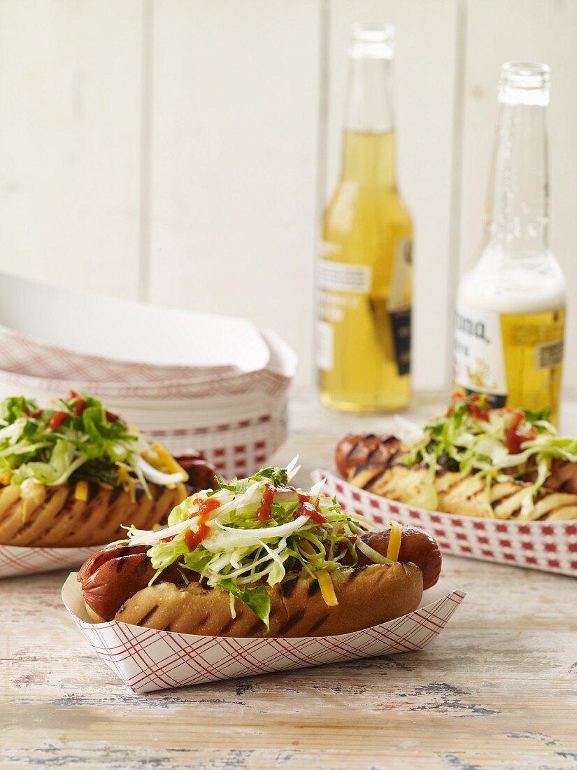 Gegrillte Hot Dogs in Pappschälchen mit Bier