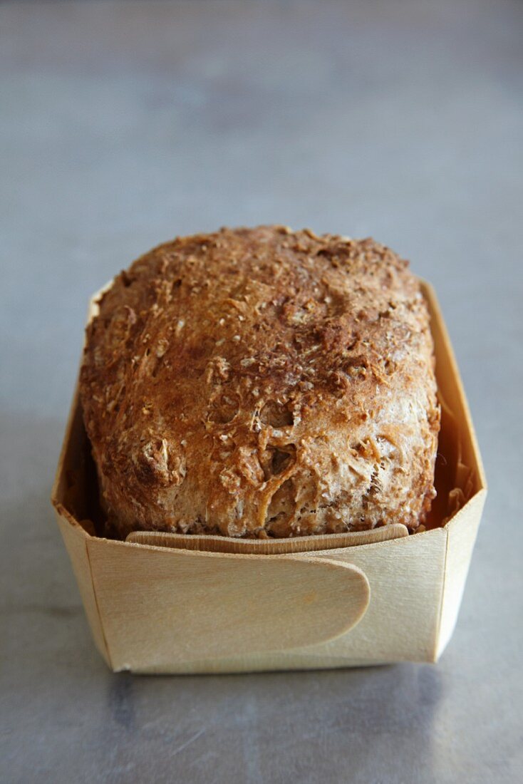 A loaf of wholemeal bread in a wooden basket