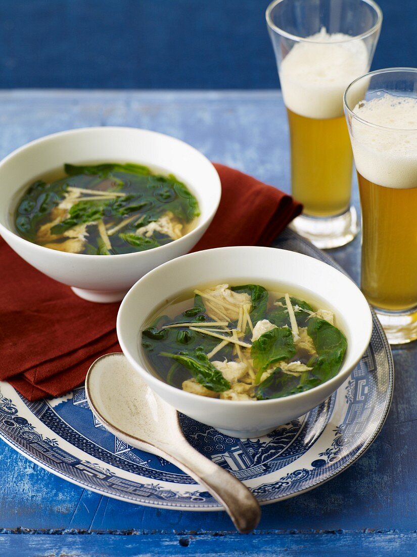 Two Bowls of Soup with Greens and Two Glasses of Beer
