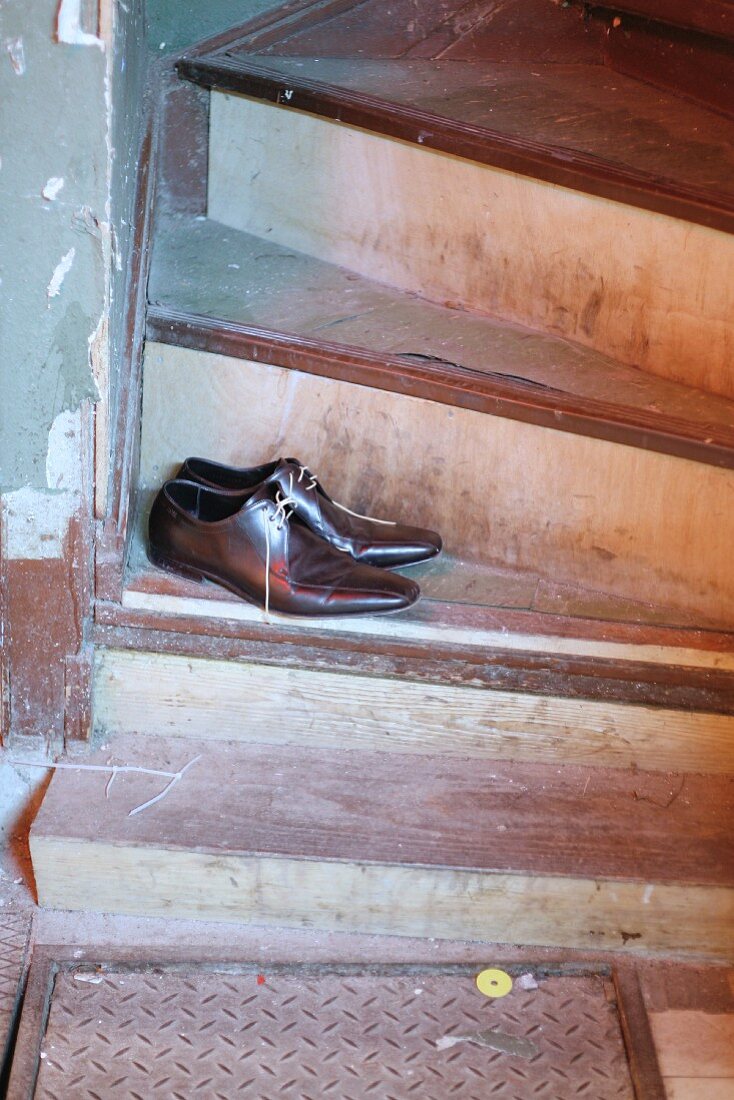 Men’s shoes threaded with spaghetti shoelaces on vintage wooden stairs