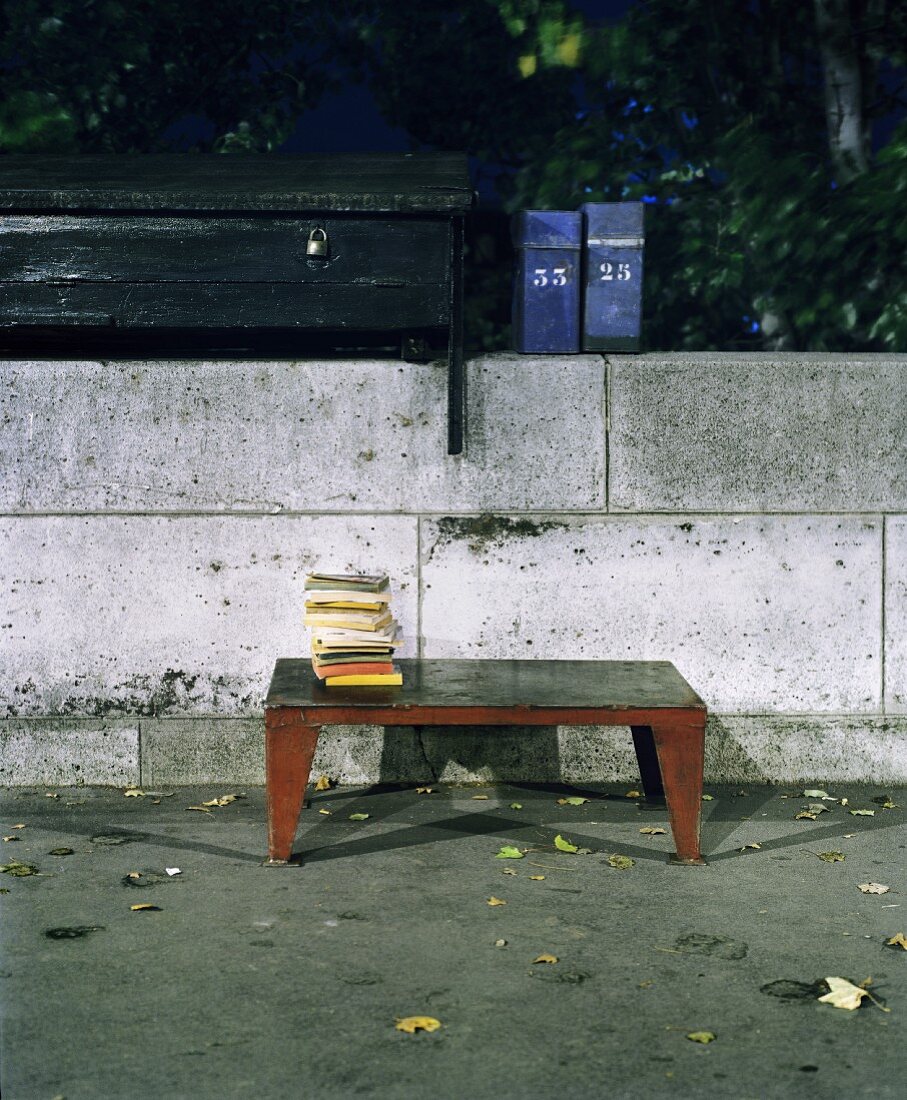 Stack of books on vintage metal coffee table in front of simple stone wall