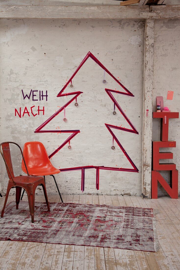 Retro Stühle vor skizziertem Weihnachtsbaum an Wand in rustikalem Ambiente