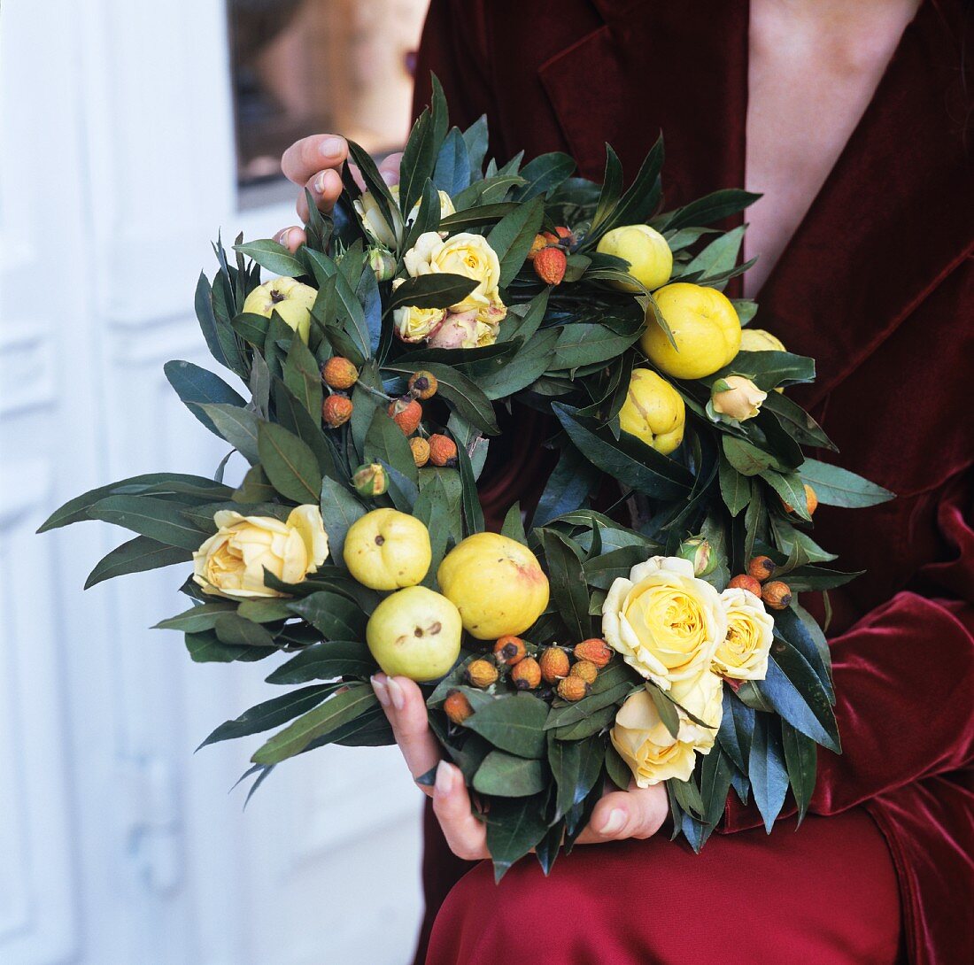 Wreath of leaves and fruit held by woman in festive clothing