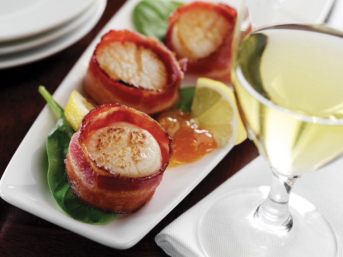 Bacon Wrapped Scallops on a Platter; Glass of White Wine
