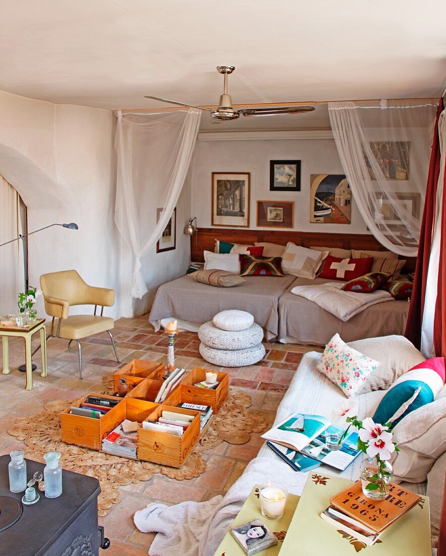 Gemütliches Tagesbett mit Kissen und improvisierter Bodentisch vor Rückzugsbereich in Nische eines mediterranen Wohnzimmers