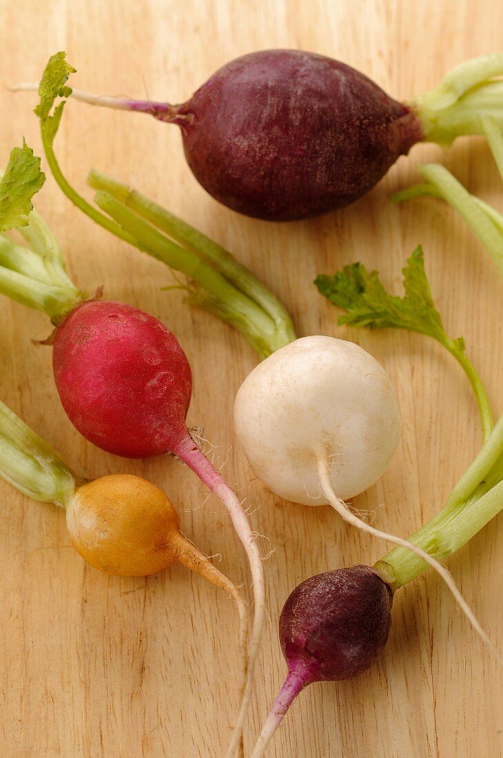 Various radishes on a wooden surface