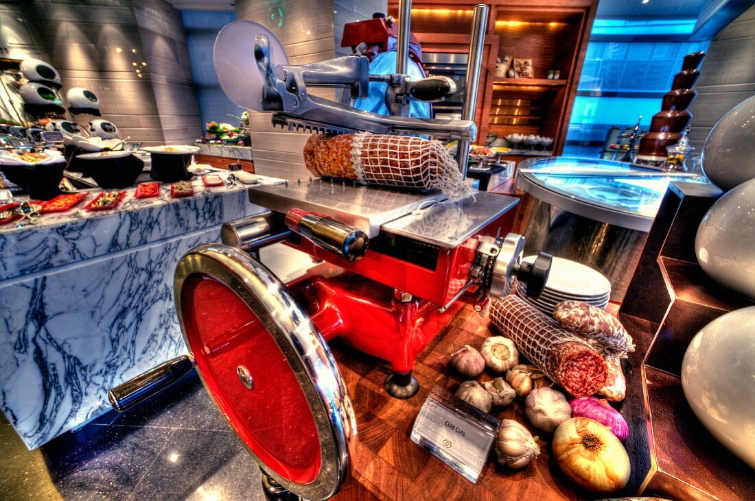 A cutting machine with salami and ham on a buffet