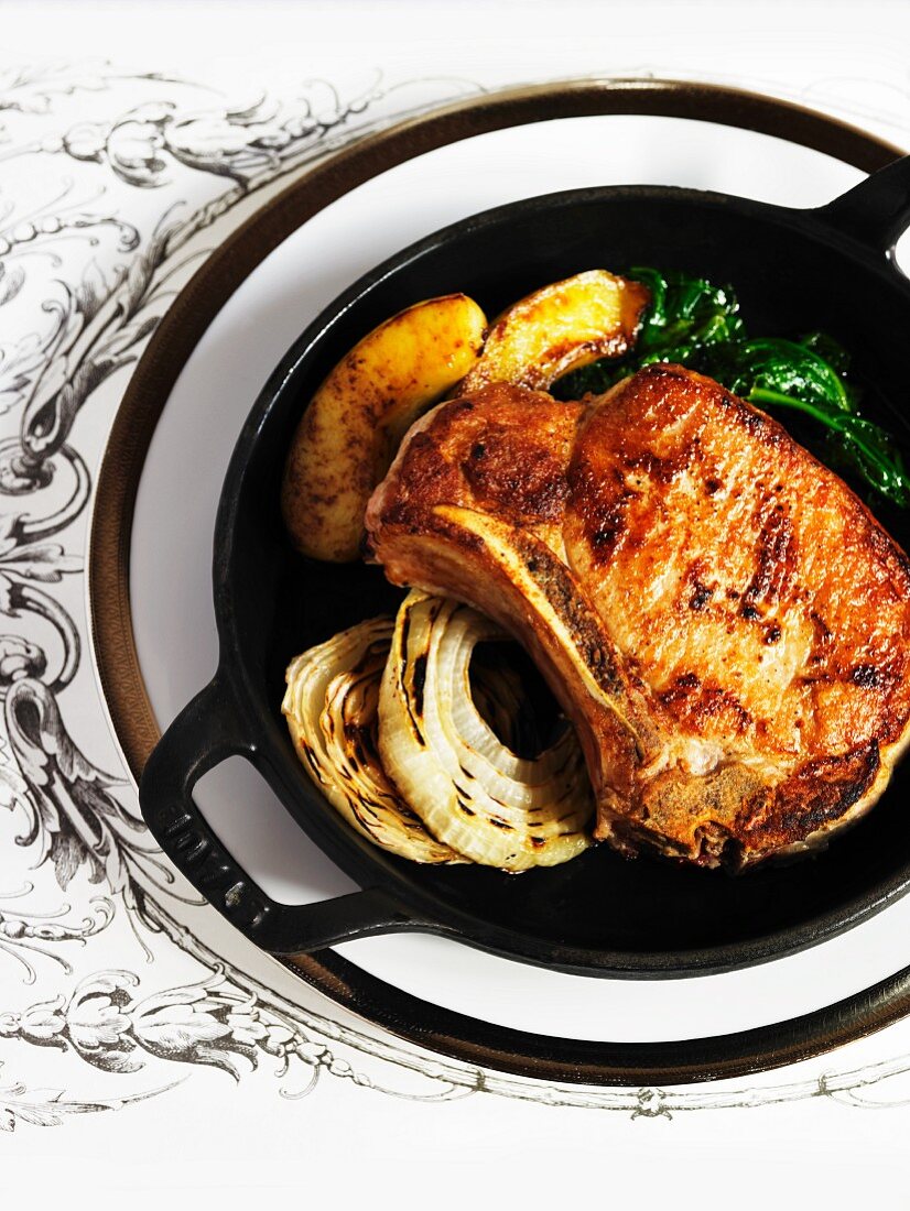 A Pork Chop in a Cast Iron Pan with Onions and Sliced Apples