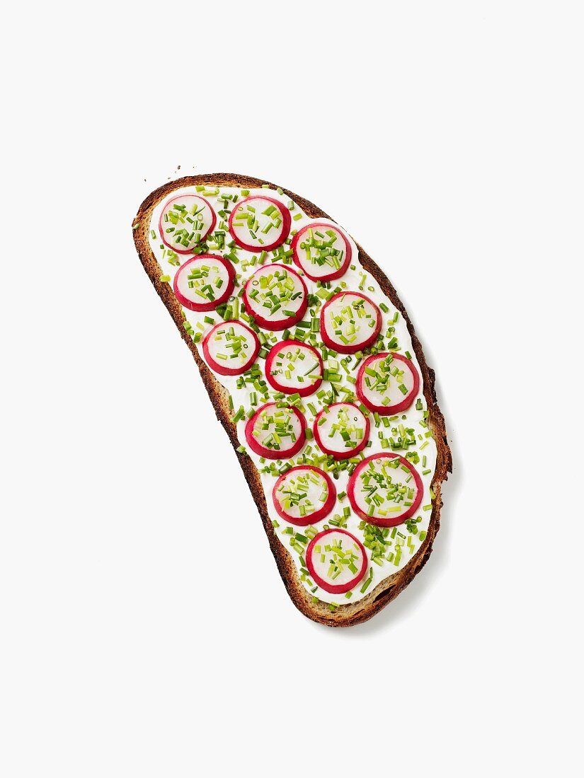 A slice of bread topped with quark, radishes and chives