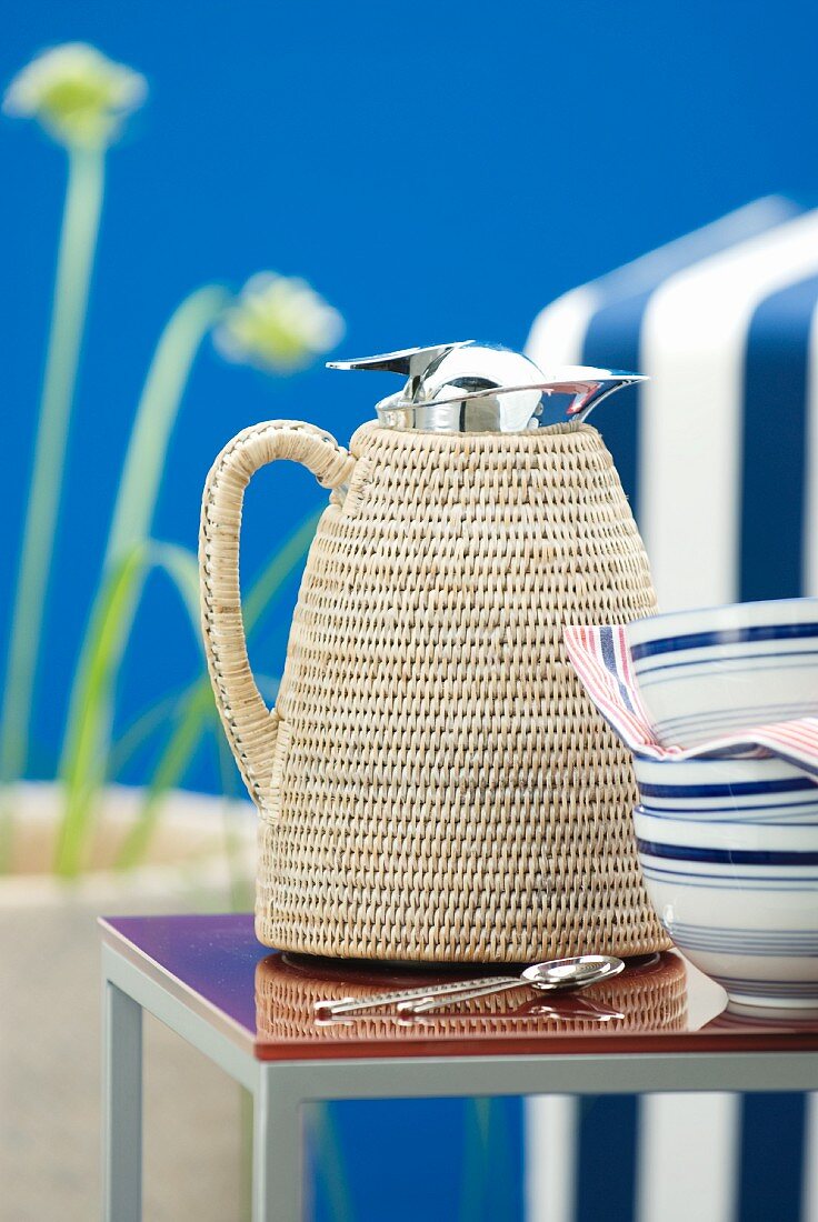 Thermos jug with raffia cover on side table