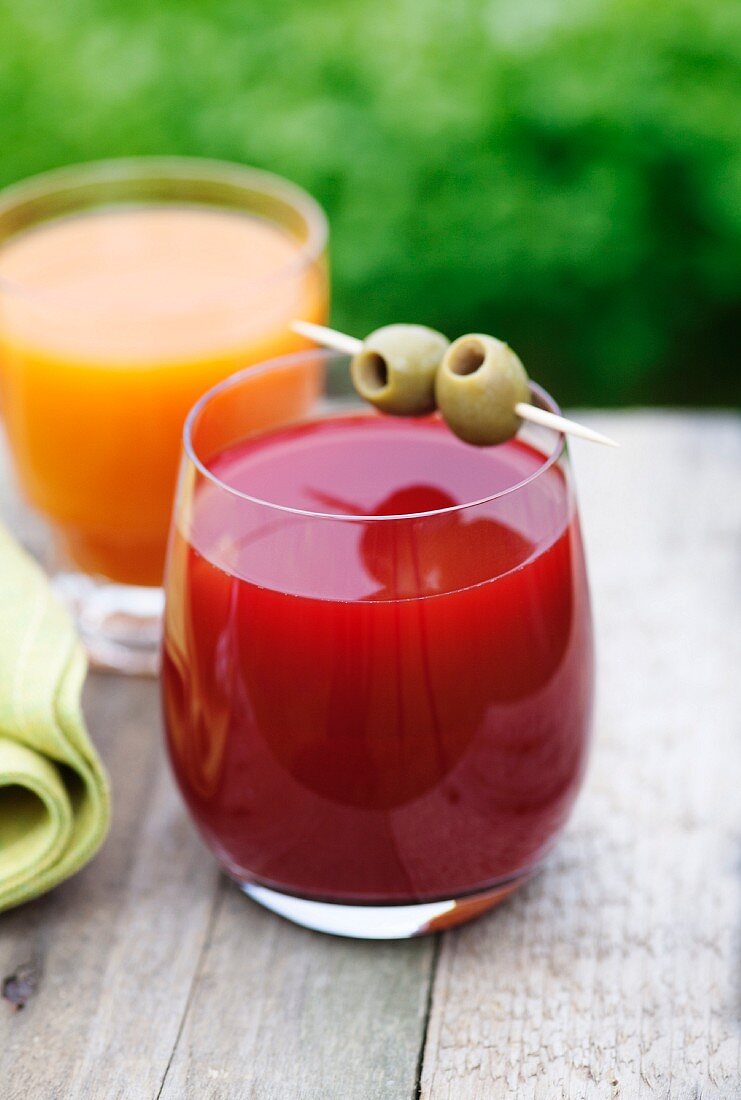 A glass of carrot and orange juice and a glass of beetroot and apple juice