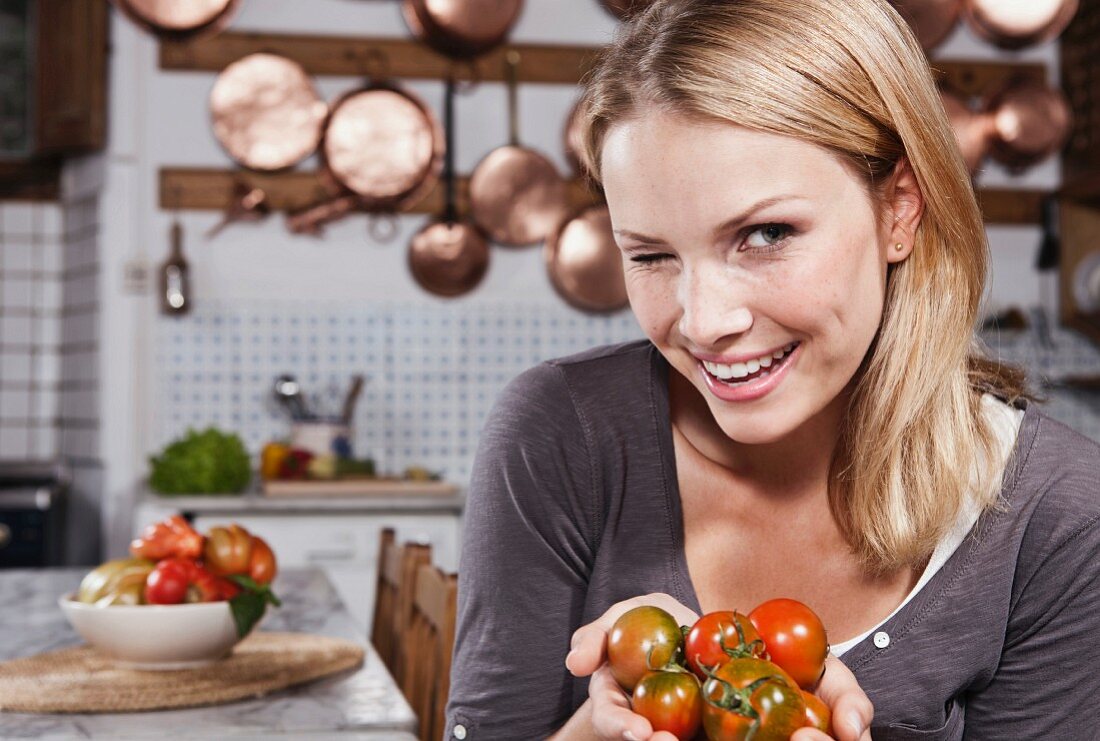 A young woman holding tomatoes winking at the camera