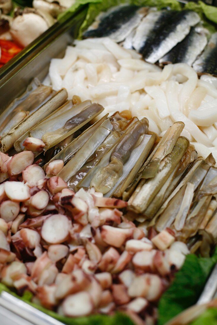 Oktopus, Schwertmuscheln, Tintenfisch und Sardinen in einer Metallschale