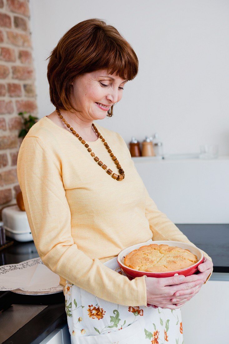 woman in kitchen smiling at cake