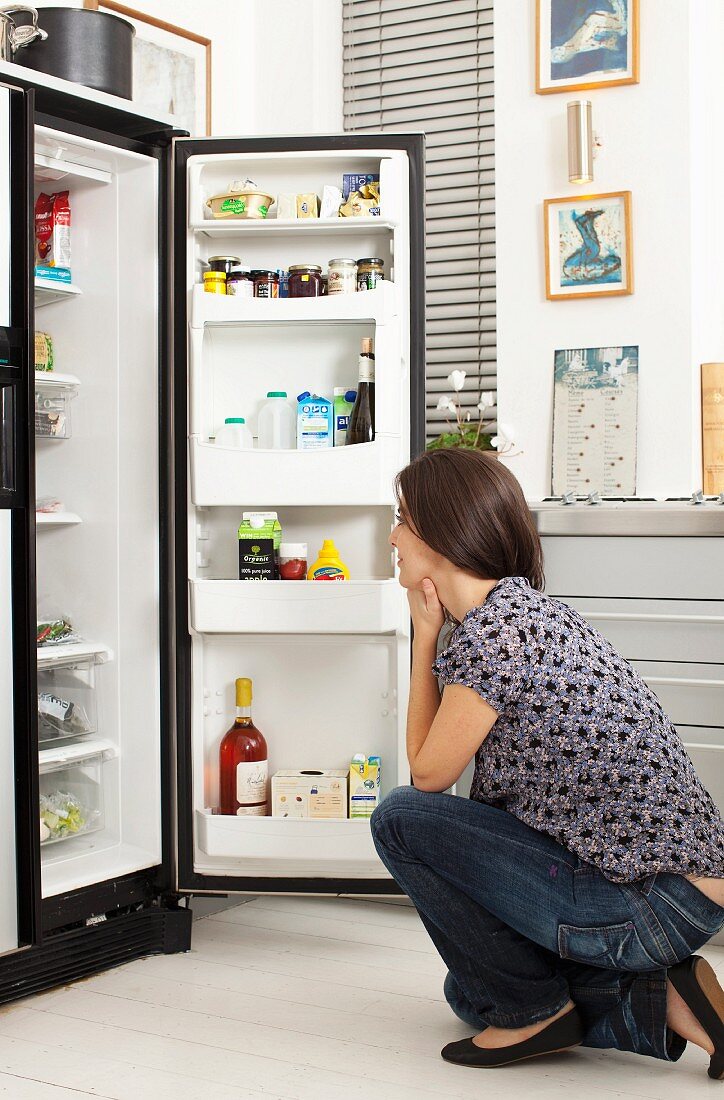Frau sucht im Kühlschrank