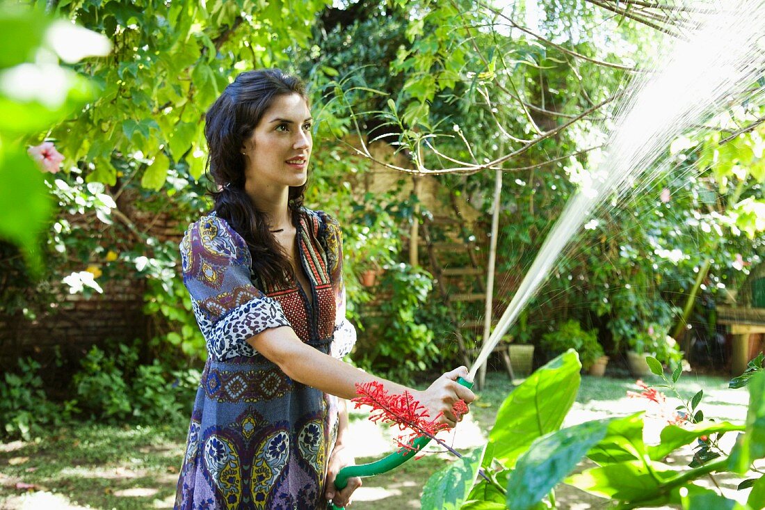 Woman watering plants in tropical garden