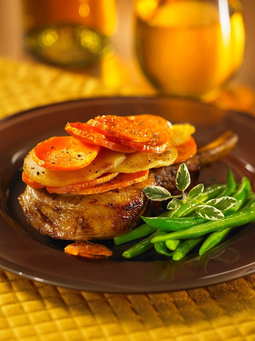 A pork chop topped with apples and sweet potatoes